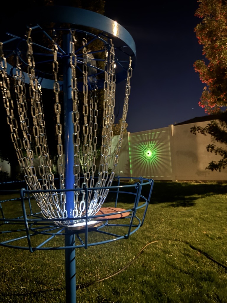 Disc golf basket illuminated at night — the scene of a late evening round at the course